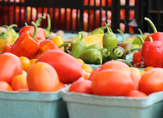 Peppers and tomatoes of various colors in trays at the farmer's market