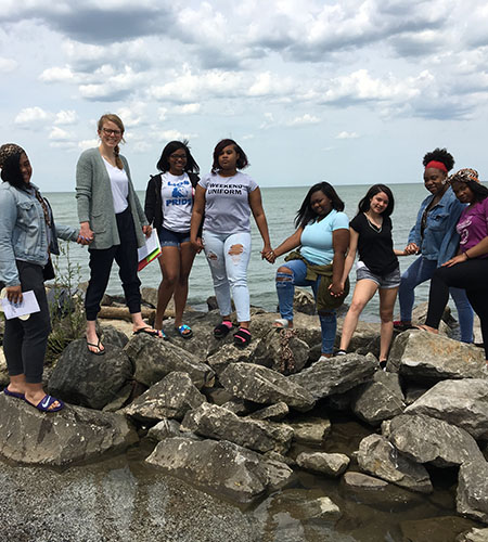 Mary Carney Sayre, shown with her students standing on rocks by the sea.