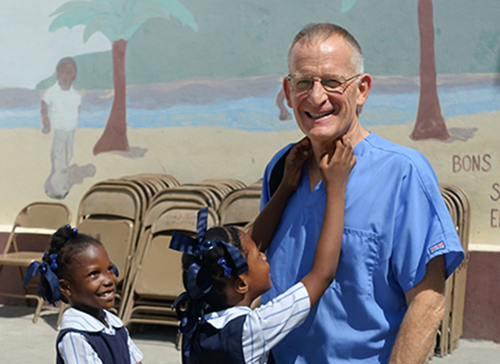 Haitian girls in school uniforms smile and laugh with the dentist.