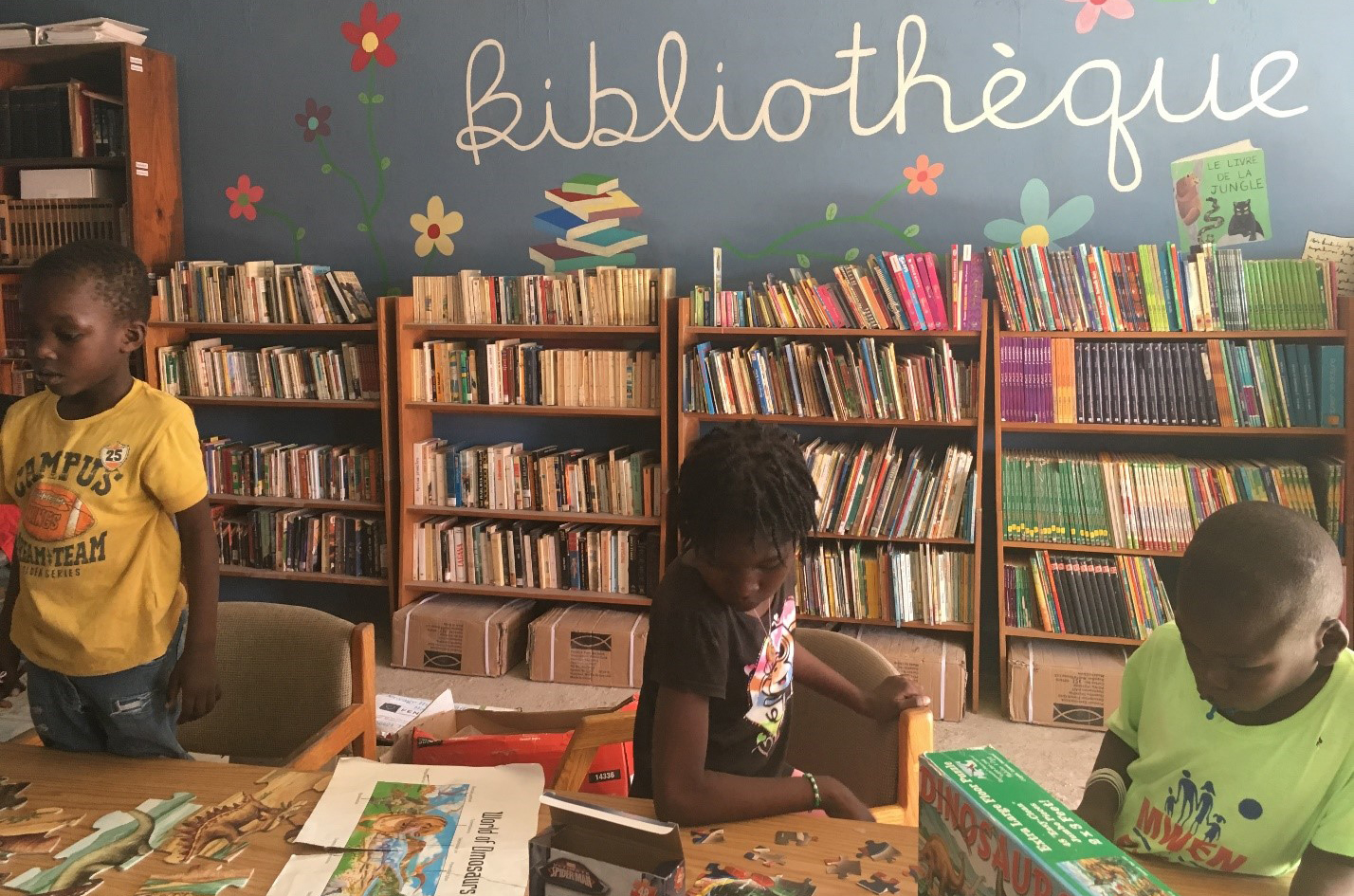 Three Haitian students around a table at the foyer library.