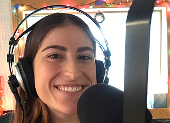 Katie smiles in front of a microphone.