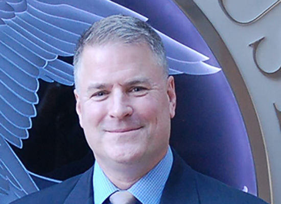 Kevin Dowling smiles in portrait, wearing a blue suit.