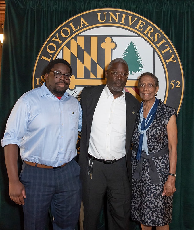 The Simms family (Tyler, Ed, and Louise) pose in front of the Loyola seal