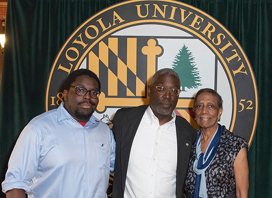 The Simms family (Tyler, Ed, and Louise) pose in front of the Loyola seal