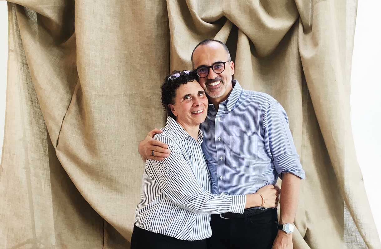 Mary and Brian hugging each other with fabric draped in the background.