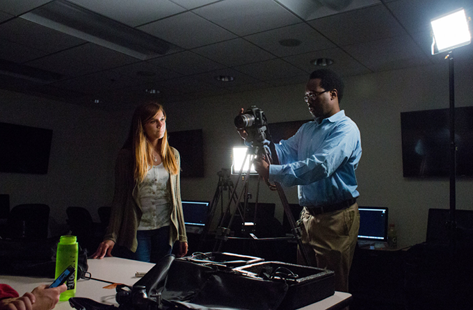 A female GreyComm member observes as her colleague adjusts a camera.