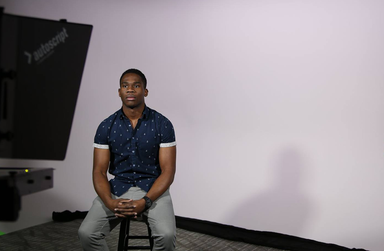 Student sits in front of light and off camera flash equipment.