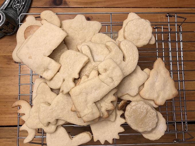 Batch of Evergreen tree and Loyola L-shaped cookies resting on a cooling rack