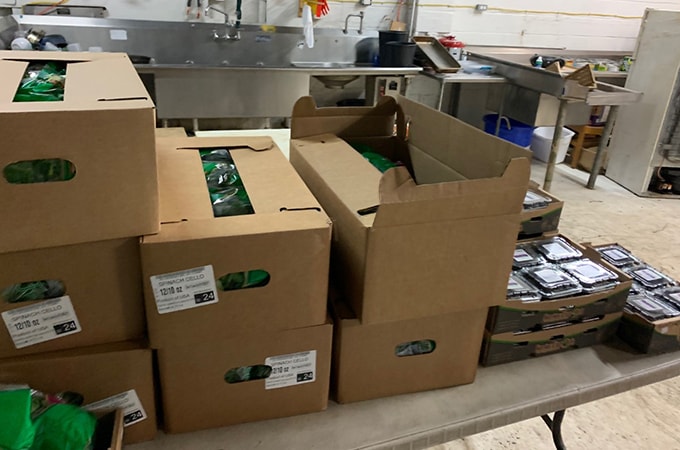 Multiple boxes full of fruits and vegetables sitting on a table in a kitchen