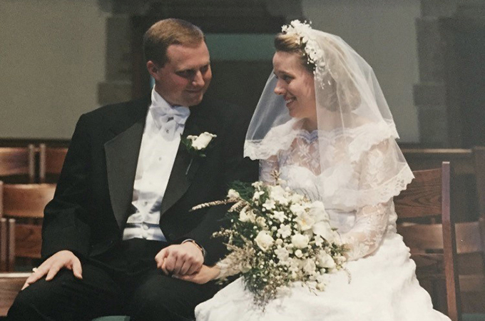 Charlie and Eileen sit in the pews wearing in their wedding clothes.