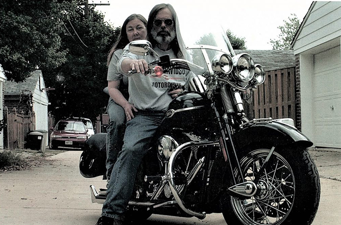 Dale and Jim Snow sit together on a motorcycle.