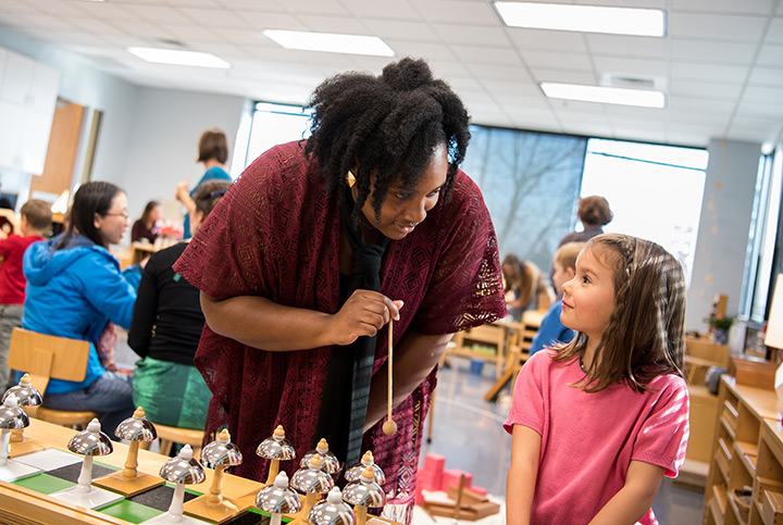 A woman teaching a young girl in a classroom