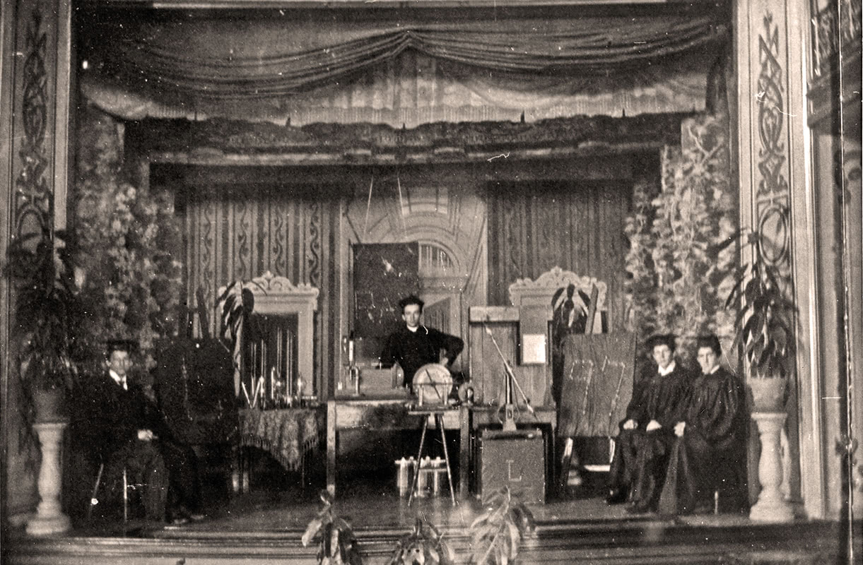 Black and white photo of students in the late 19th century posing in front of an x-ray machine