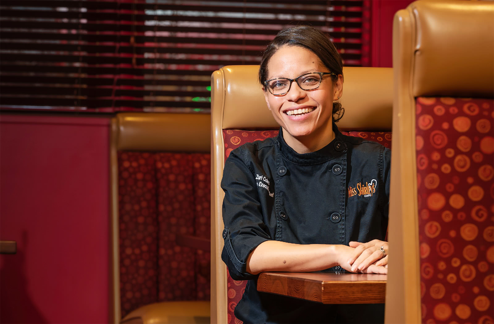 Zuri Coles sits in a booth in the restaurant Miss Shirley's Cafe while posing for a photo