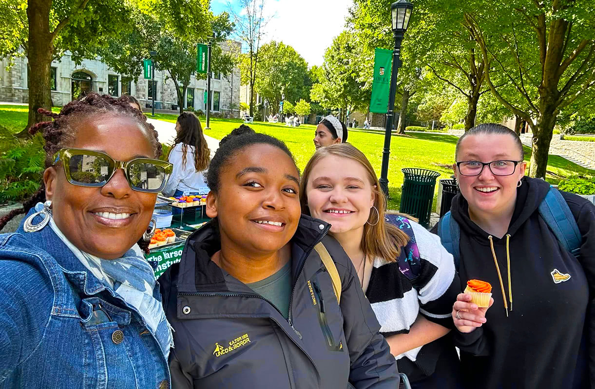 Kaye Whitehead and a small group of students pose for a selfie while on Loyola's quad