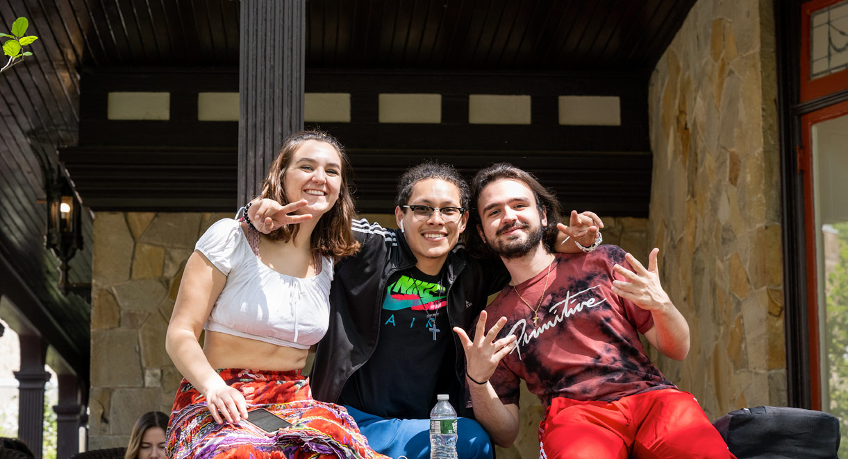 Students sit on the porch of the humanities building