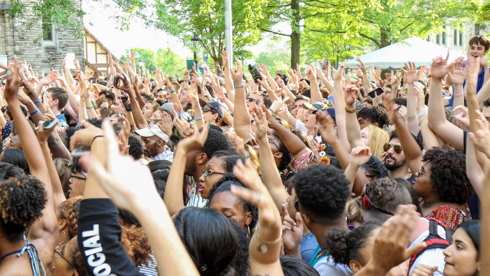 A large gathering of people at Loyolapalooza cheering with hands in the air