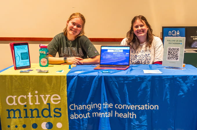 Two students in Active Minds presenting information about mental health awareness at a tabling event.