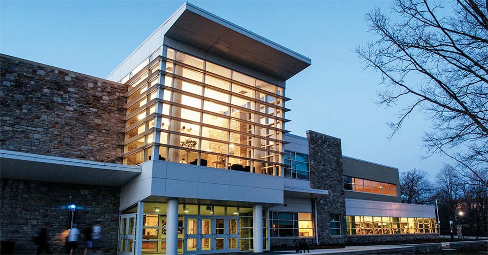 The front of the Fitness and Aquatic center at dusk, with the interior lights glowing through the windows