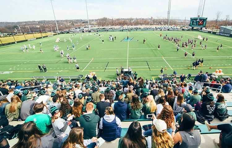 An grassy athletic field with players as seen from the crowd