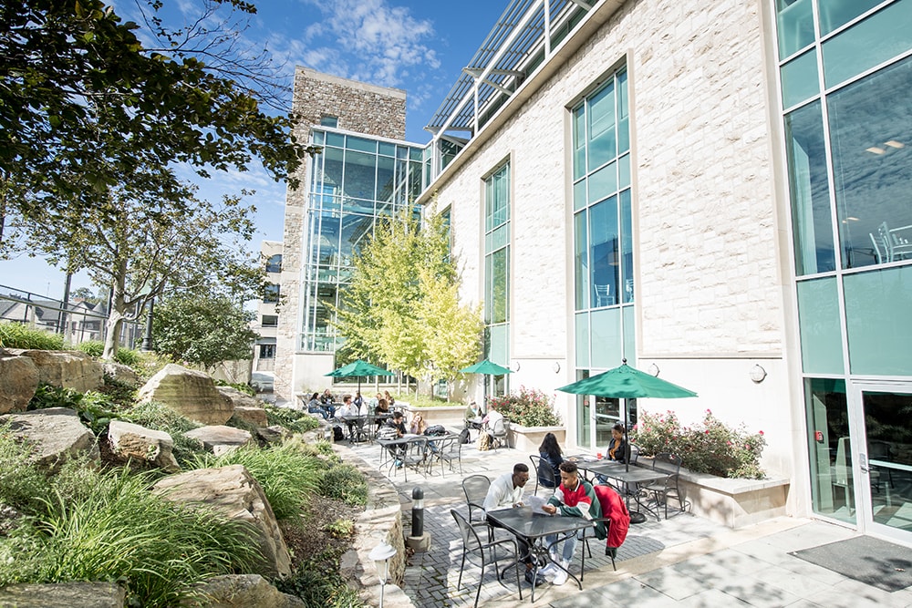 Students sitting at tables outside the student center on a sunny day