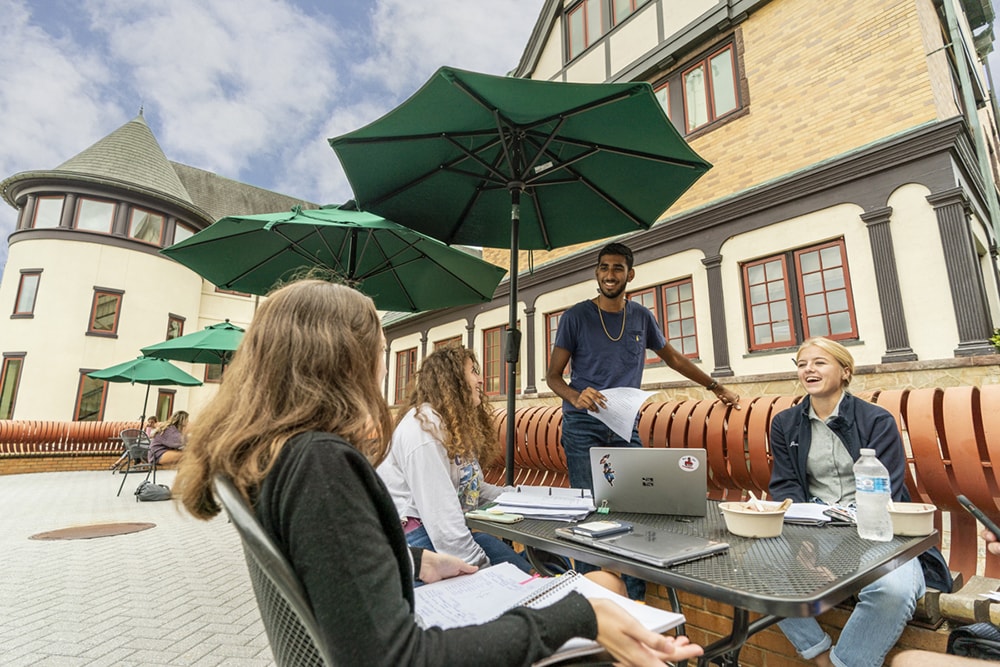 Students sitting and laughing at the benches by the Humanities Building