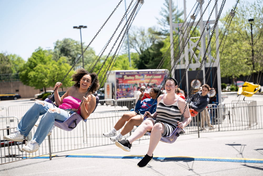 Students laughing and riding on an amusement ride at Loyolapalooza