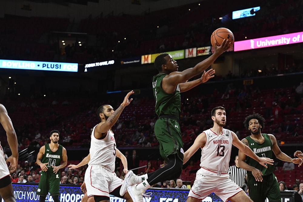 A member of the Loyola men's basketball team jumps past defenders for a layup