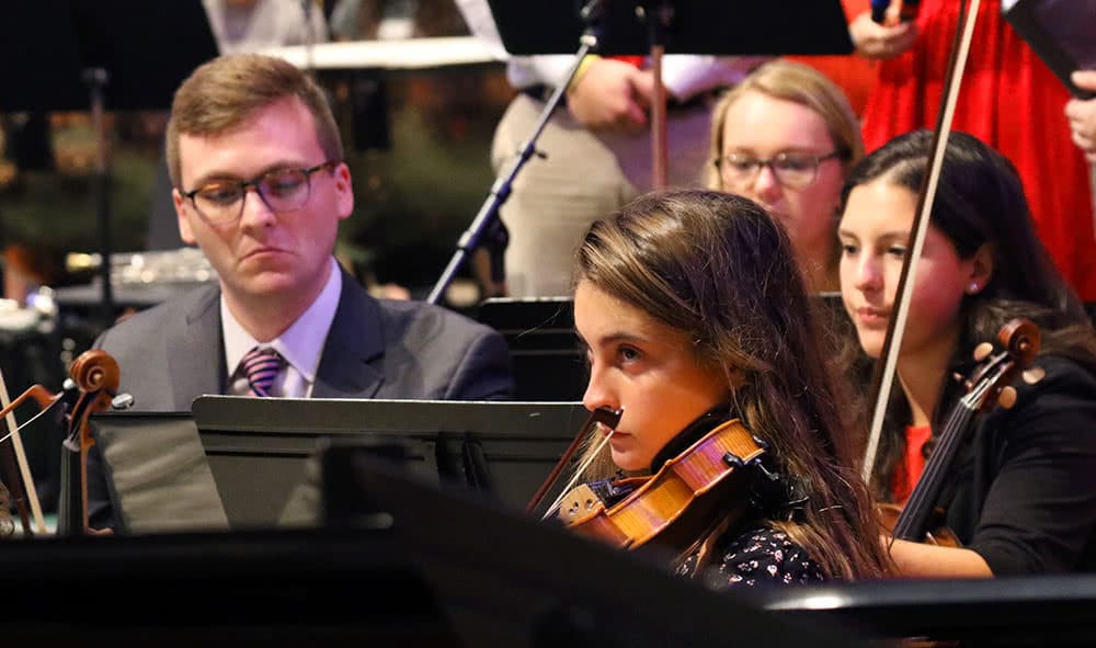 Students holding string instruments during a concert