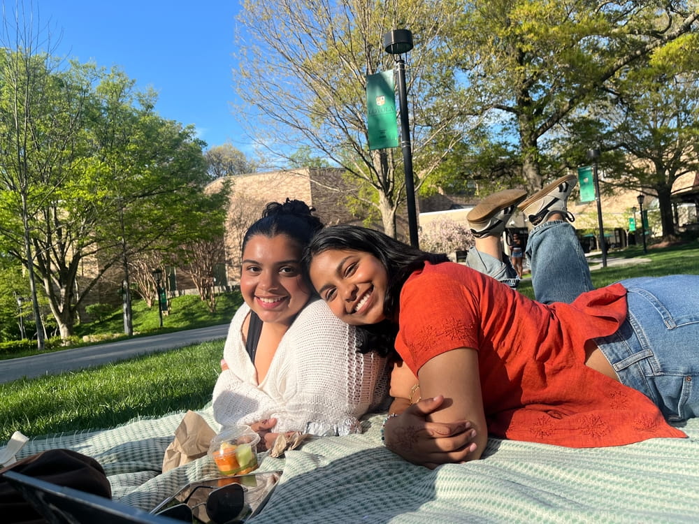 Students relaxing on a blanket on the Quad, smiling for the camera.
