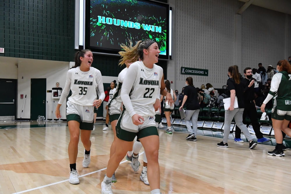 Members of Loyola's women's basketball team celebrate a victory on the court of Reitz Arena.