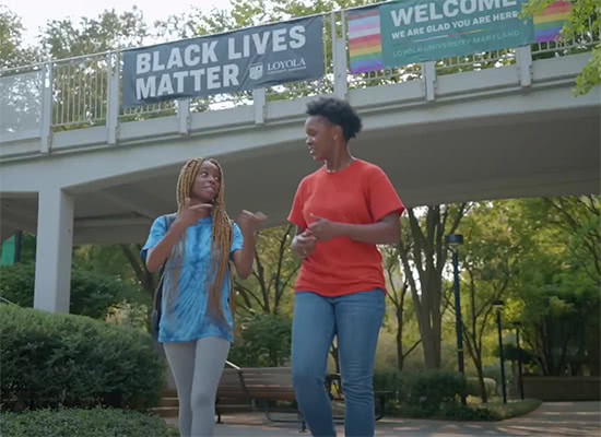 Two female students chat while walking on campus