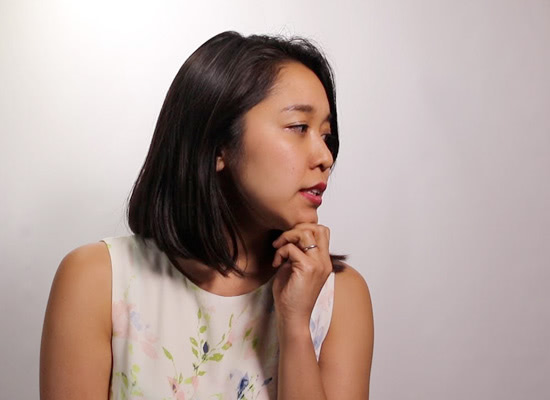 A female professor looks to the side in front of a white backdrop