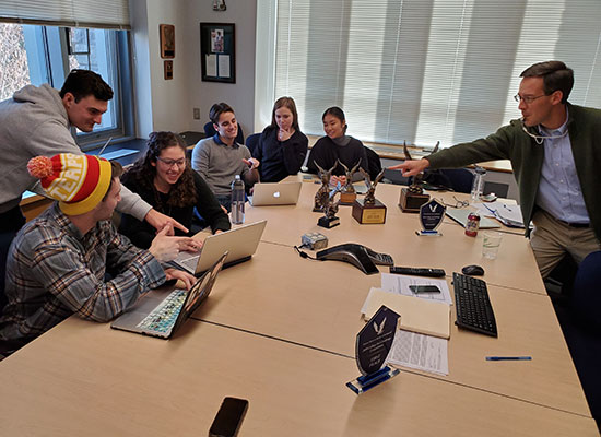 Members of Loyola's Fed Challenge Team practice at a conference table as faculty proctor, John Burger acts as referee