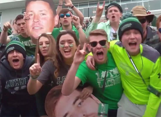 Students cheering in the stands while wearing face paint and Loyola shirts