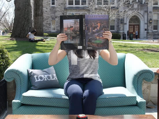 Student sitting in a chair outside while reading a book