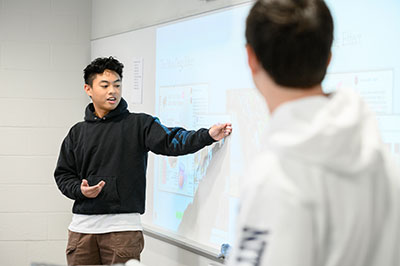 Student explaining something at the board in a bright, clean classroom