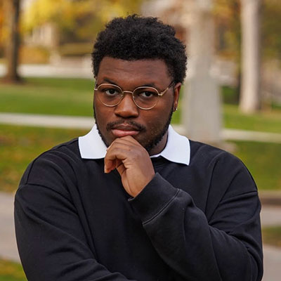 Demetrius poses on the quad with a raised hand and serious face