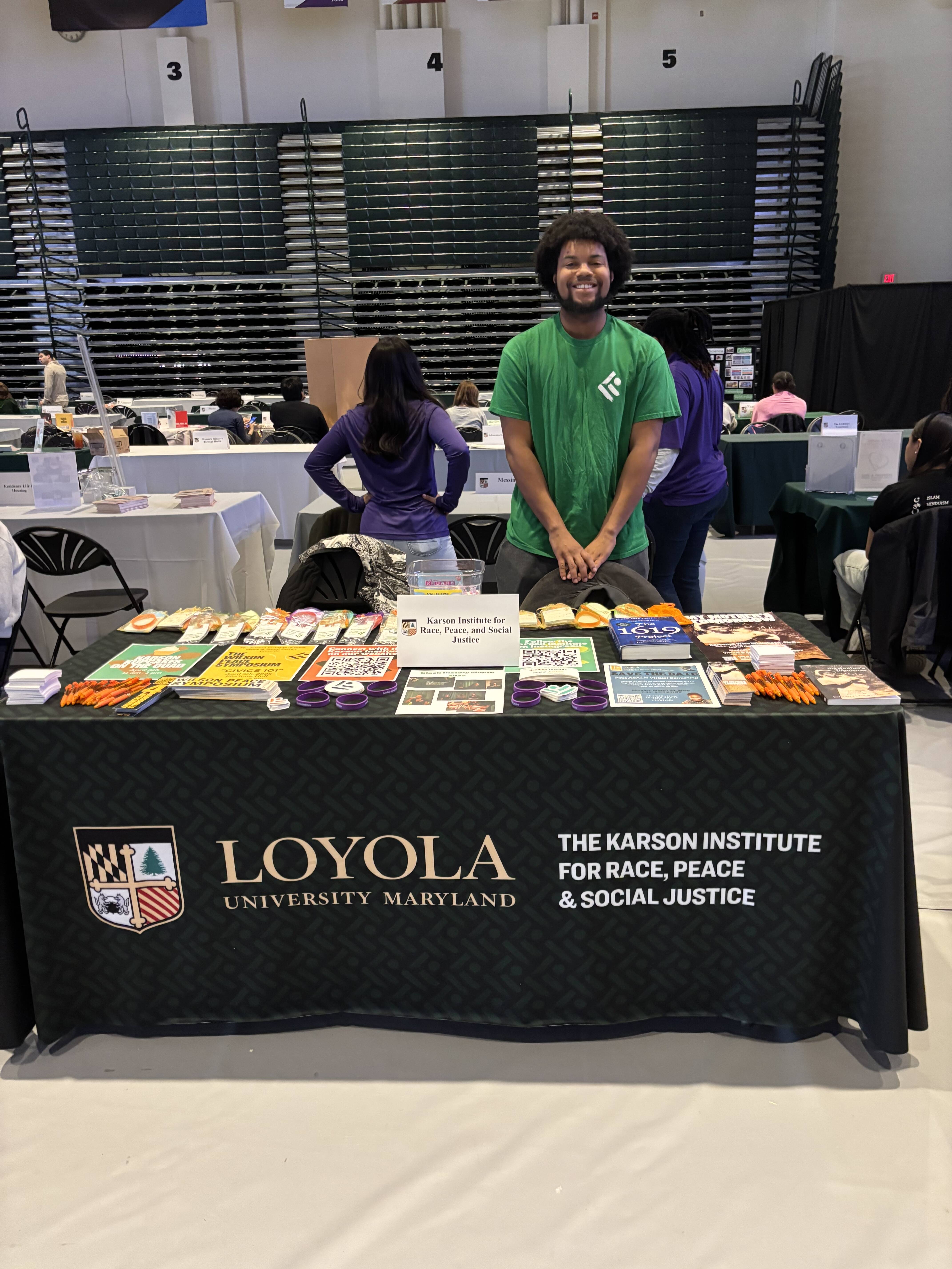 Gavin Williams standing at the Karson Institute's Table during Loyola University Maryland's Accepted Students Day in the Reitz Arena