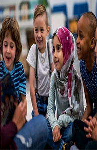 Smiling children listening to an instructor while all sitting on the floor