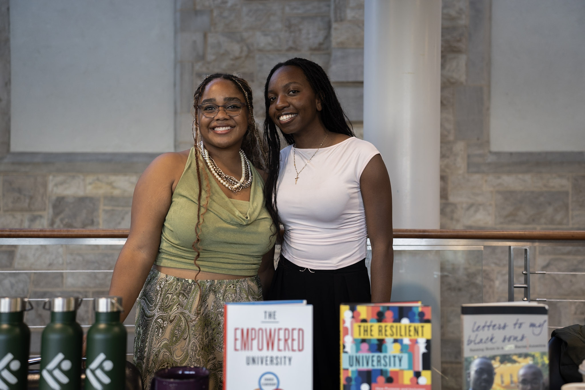 Student Interns Amaya Guess and Sarah Naje tabling for the event Student Interns Amaya Guess and Sarah Naje smiling while tabling for the event
