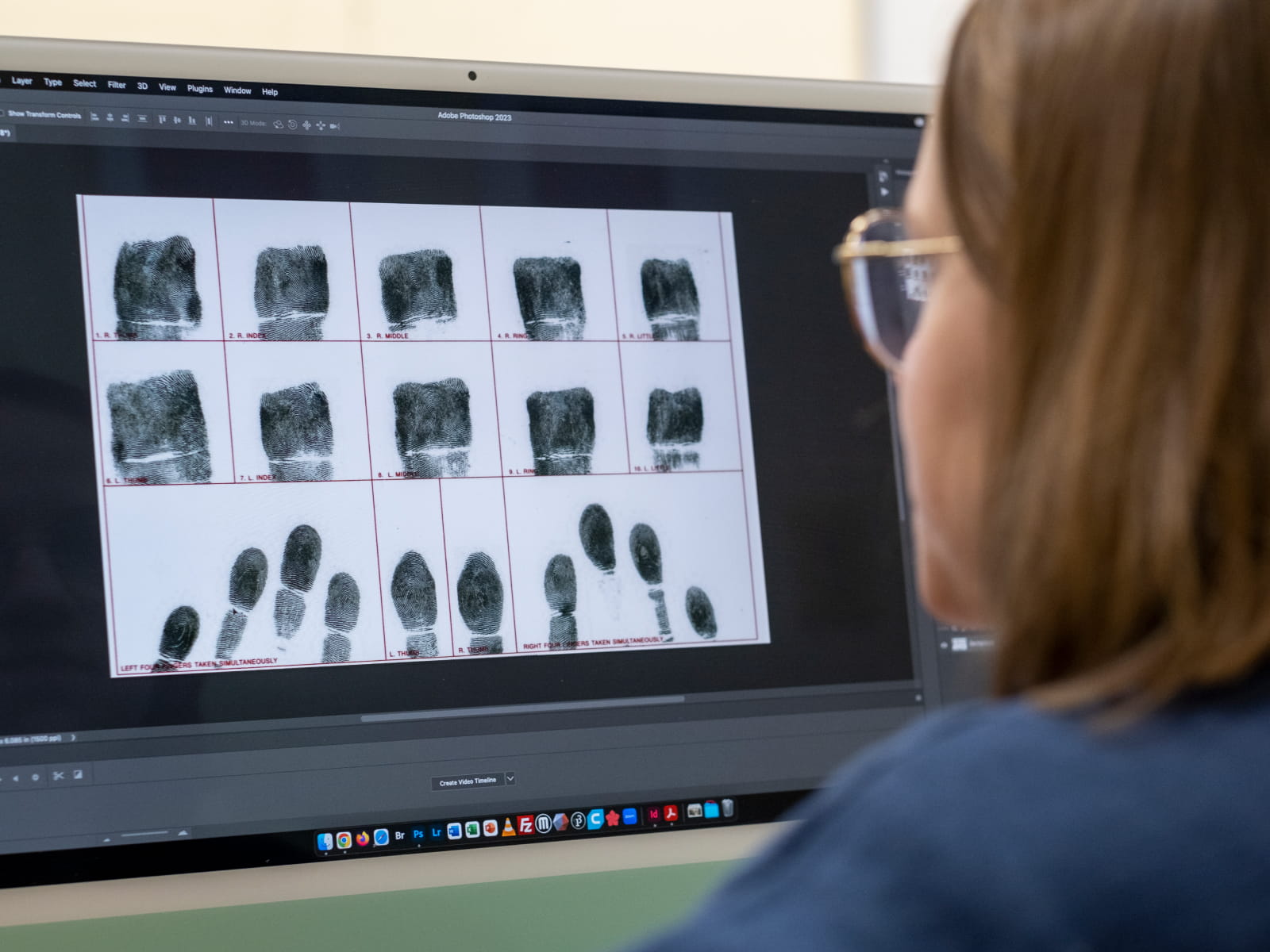 A student in glasses compares fingerprints on a computer screen