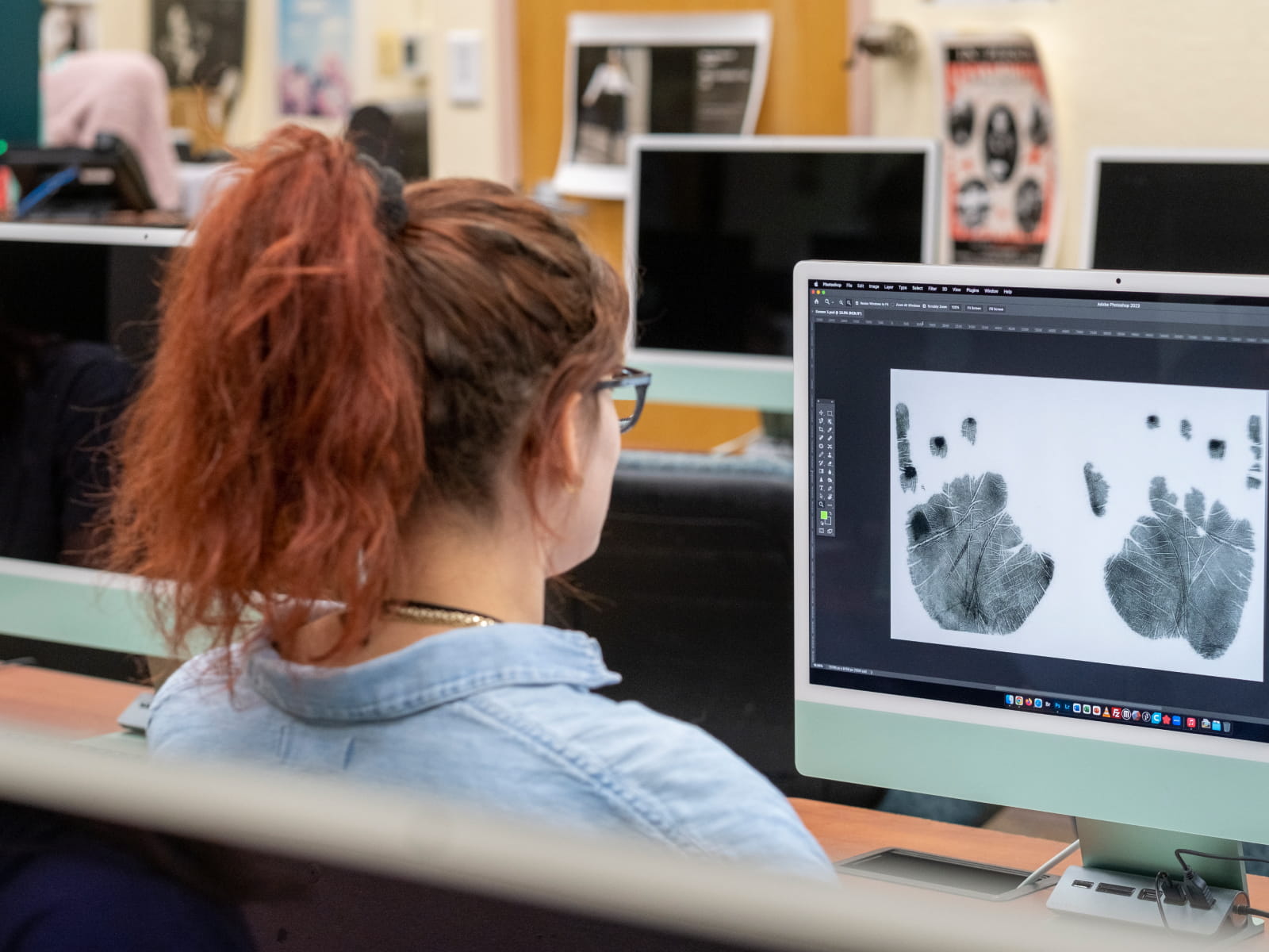 A woman looks at a computer screen with handprints open in computer software