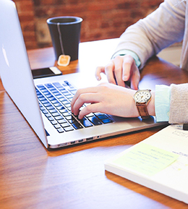 Person working with a laptop, notebook, and coffee