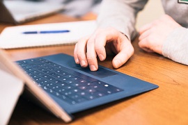 Student hand controls mouse by laptop