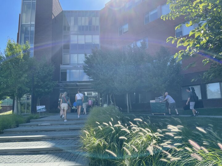 Members of the class of 2026 moving onto campus in front of Thea Bowman hall with some parents on a beautiful sunny day