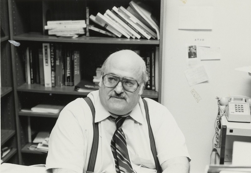 Black and white photo of Andrew Ciofalo sitting in his office at Loyola