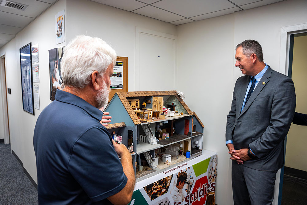 David Rivers, Ph.D., chair and professor of forensic science, and Johnny Olszewski, Jr., U.S. Representative for Maryland’s 2nd Congressional District, look at a miniature crime scene model (Aaron Boutwell)