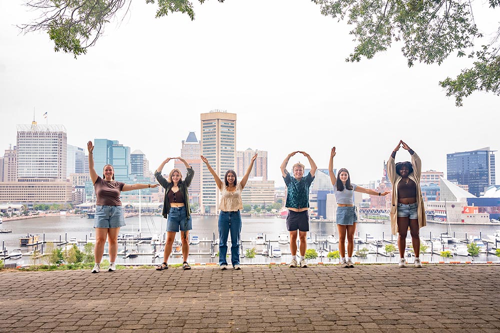Students stand and spell out L O Y O L A with their arms