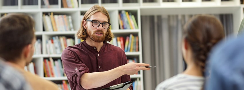 Male administrator speaking to employees in library